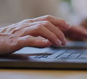Close-up of hands typing on a laptop keyboard.