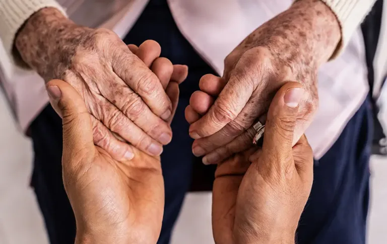 Close-up of two people holding hands, showing support and connection.