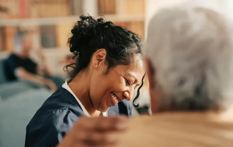 Woman smiling warmly while sitting beside an older adult.