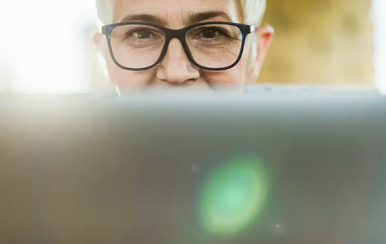 Close-up of a person with glasses looking over a laptop screen.