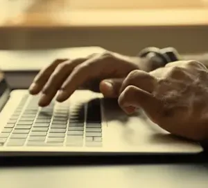 Close-up of hands typing on a laptop keyboard.
