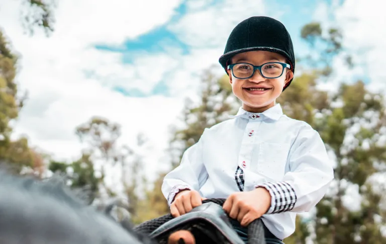 girl rides on horse wearing black helmet and white shirt